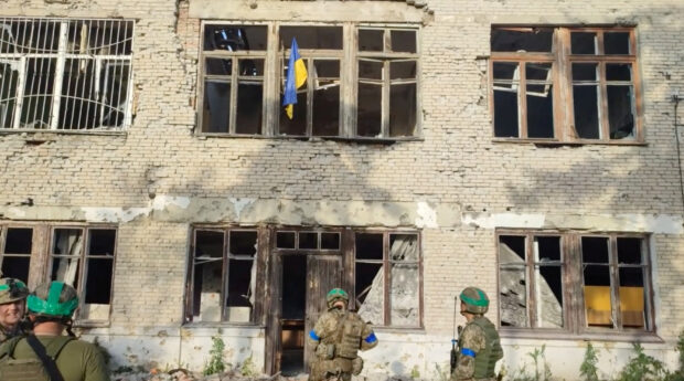 Ukrainian soldiers stand in front of a building with a Ukrainian flag on it, during an operation that claims to liberate the first village amid a counter-offensive, in a location given as Blahodatne, Donetsk Region, Ukraine, in this screengrab taken from a handout video released on June 11, 2023. 68th Separate Hunting Brigade 'Oleksy Dovbusha'/Handout via REUTERS