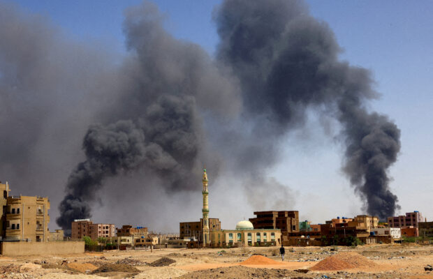 A man walks while smoke rises above buildings after aerial bombardment, during clashes between the paramilitary Rapid Support Forces and the army in Khartoum North, Sudan, May 1, 2023. REUTERS/Mohamed Nureldin Abdallah