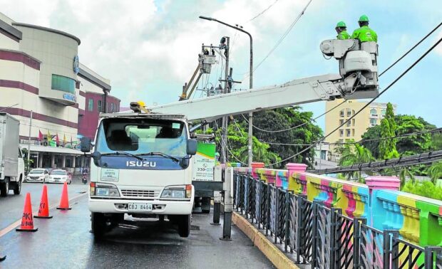 DAY’S WORK Linemen of More Electric and Power Corp.,in this May 21 photo, check power lines at La Paz District in Iloilo City in a bid to improve its service to Ilonggos. —PHOTO COURTESY OF MORE POWER ILOILO electricity