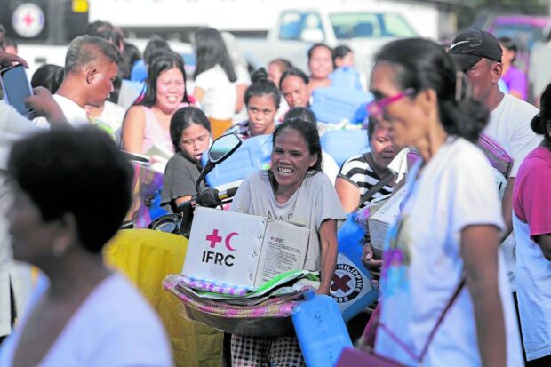 ESSENTIALS Villagers who left their communities within the danger zone of Mt. Mayon in Guinobatan, Albay, on Tuesday receive hygiene materials, blankets and water jugs from the Philippine Red Cross at a community college that will become their temporary home while the volcano remains restive. —MARK ALVIC ESPLANA