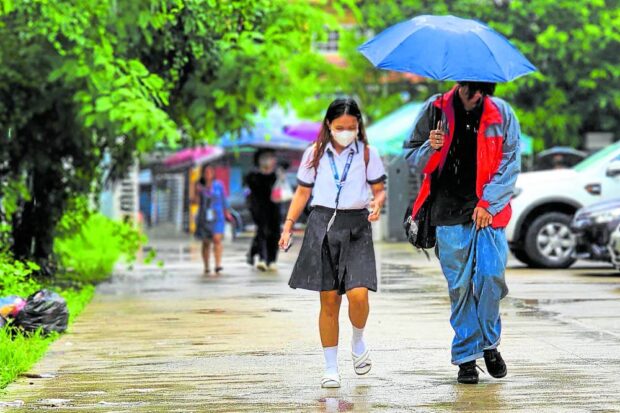 UMBRELLA DAY Students of Dagupan City National High School use umbrellas to shield themselves from the rain dumped by the enhanced southwest monsoon, or “habagat,” in this photo taken on Tuesday. The biggest secondary school in Dagupan opted to continue holding classes despite the inclement weather, unlike other schools in at least 10 localities in Pangasinan province that suspended classes due to heavy rains. —WILLIE LOMIBAO