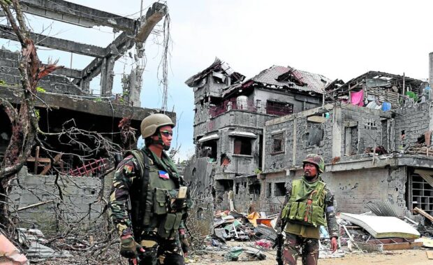In this photo taken on Oct. 8, 2017, soldiers patrol a section of the city center of Marawi as government forces continue to battle members of Islamic State-linked groups that laid siege to the provincial capital of Lanao del Sur. STORY: Compensation process for Marawi folk starts