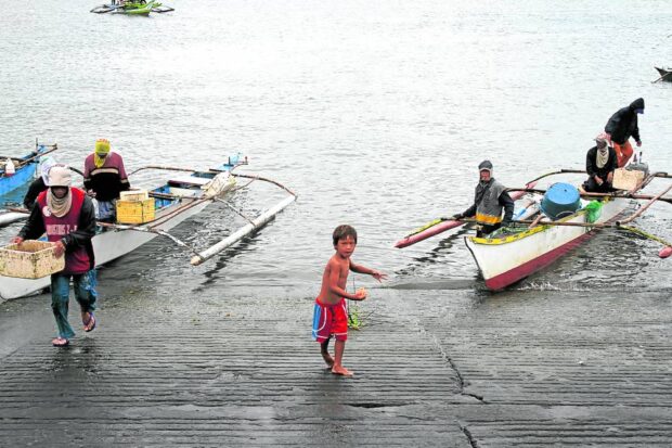 TYPICAL DAY A group of fishermen in Lucena City unloads fresh catch in a coastal village on Thursday after a fishing trip in Tayabas Bay. —DELFIN T. MALLARI JR.