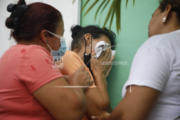 Relatives of inmates wait in distress outside the entrance to the women's prison in Tamara, on the outskirts of Tegucigalpa, Honduras, Tuesday, June 20, 2023. A riot at the women's prison has left at least 41 inmates dead, most of them burned to death, a Honduran police official said. (AP Photo/Elmer Martinez)