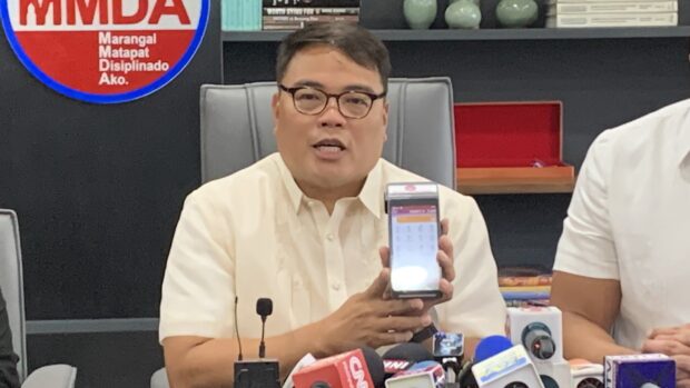 Metropolitan Manila Development Authority acting chairman Romando Artes, in a press briefing in Pasig City on Friday, shows one of the handheld devices to be used for the single ticketing system. (INQUIRER.net photo / Noy Morcoso)