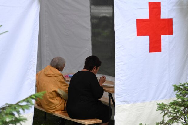 Local residents eat in a tent set outside an apartment building in the western Ukrainian city of Lviv, on July 7, 2023, a day after it was partially destroyed by a missile strike. The missile strike killed 10 people after the biggest Russian missile attack on civilian infrastructure in the western Ukrainian city since the invasion. (Photo by YURIY DYACHYS