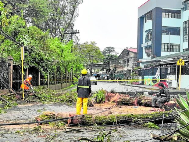 BAGUIO IMPACT Linemen of Benguet Electric Cooperative help clear a road and reconnect power lines on Thursday, a day after “Egay” also left serious damage in the summer capital. —Allan Macatuno