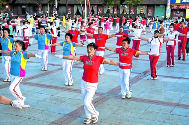 FIVE, SIX, SEVEN, EIGHT . . . Local residents taking part in an aerobics exercise called “Jiamusi Happy Dancing” at a square in northeastern China’s Heilongjiang province on July 3. Hundreds of dancers twirl in unison by a riverside, thrusting hips and shimmying shoulders in a bizarre but beloved fitness regimen that has taken the country by storm. —AFP