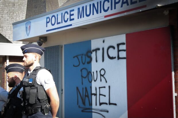 Municipal police officers stand outside a police station bearing the inscription "Justice for Nahel", in the city of Lisieux, northern France, on July 6, 2023, several days after protests that followed the shooting of a teenage driver in the suburb of Nanterre on June 27. (Photo by LOU BENOIST / AFP)
