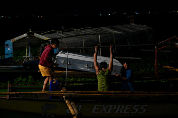 Men carry the coffin of a victim of the capsized wooden boat at Binangonan Port, Rizal province early on July 28, 2023. A small boat capsized in a lake near the Philippine capital on July 27, 2023, killing 23 people on board and leaving six others missing, rescuers said. (Photo by JAM STA ROSA / AFP)