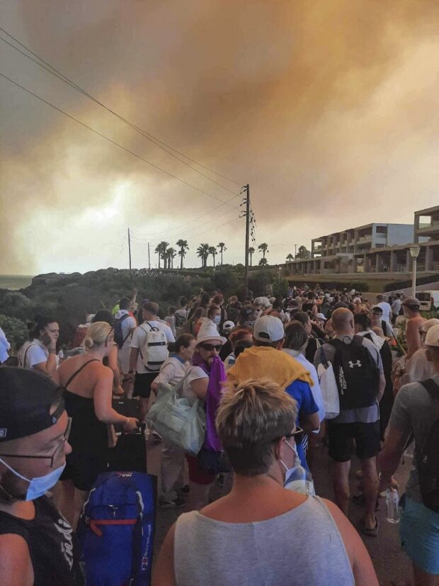 Tourists are evacuated from hotels during a wildfire on the Greek island of Rhodes on July 22, 2023. Three coastguard boats were leading more than 20 vessels in an emergency evacuation effort to rescue people from the Greek island, where fire has been raging out of control for five days.