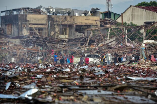 People look at the aftermath of destroyed homes after an explosion ripped through a firework warehouse, killing nine people and injuring more than 100, in Sungai Kolok district in the southern Thai province of Narathiwat on July 29, 2023. (Photo by Madaree TOHLALA / AFP)