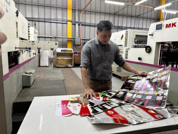 BIR Commissioner Romeo Lumagui Jr. inspects various prints of cigarette packs illegally produced by two cigarette companies located at the Subic Bay Freeport Zone.