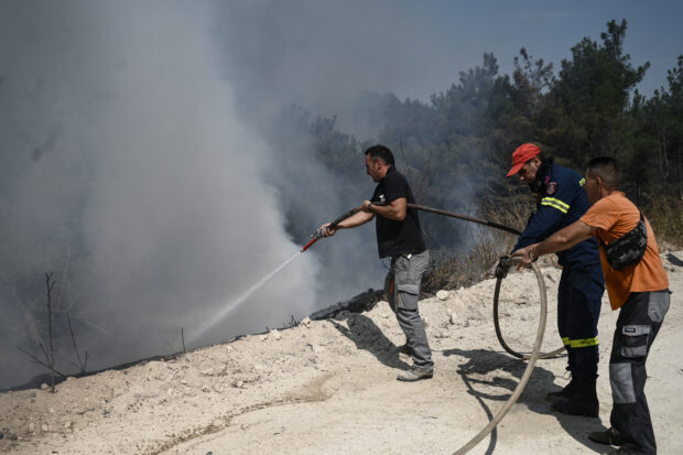 Firefighters and volunteers combat a wildfire spreading in the Dadia forest, one of the most important areas in Europe for birds of prey, as wildfire rages, in Dadia near Alexandroupoli, north Greece, on August 24, 2023. Hundreds of firefighters in Greece struggled Thursday to tame major wildfires burning for a sixth day, leaving 20 dead and prompting growing outrage among stricken residents. (Photo by Sakis MITROLIDIS / AFP)