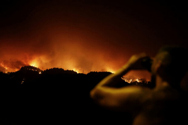 Samuel, 34, uses binoculars in the village of La Victoria, as wildfires rage out of control on the island of Tenerife, Canary Islands, Spain August 19, 2023. REUTERS/Nacho Doce