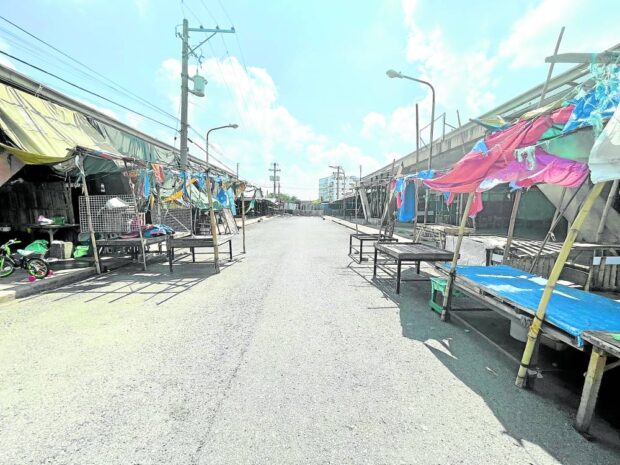 NO SIGN OF ACTIVITY All is quiet at the Tarlac City public market after the local governmentclosed and fenced it in October 2022 over water pollution and lack of business permit by a private operator. Some shoppers who come to the market, where a fewvendors remain, risk being hurt by using gaps in the fence and barricade to enter and leave the premises. —PHOTOS BY TONETTE T. OREJAS