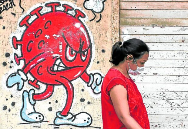 A woman walks past a coronavirus-themed graffiti, amidst the spread of the COVID-19 pandemic, on a street in Mumbai, India, Oct. 12, 2021.