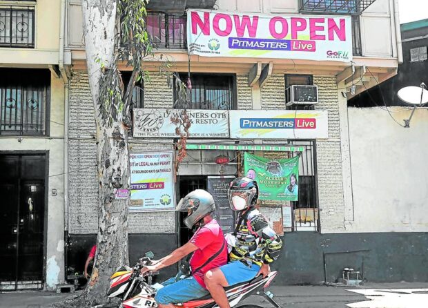 In this photo taken in May 2022, motorists ride past an online “sabong” center in Paco, Manila, which has remained closed on orders of President Marcos.