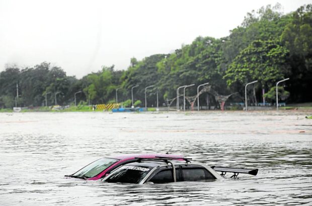 CAN’T DRIVE THESE Owners of these cars left at a riverside park in Marikina City have failed to bring their vehicles to higher ground as water level in Marikina River starts rising on Thursday morning amid heavy rains in Metro Manila. —LYN RILLON