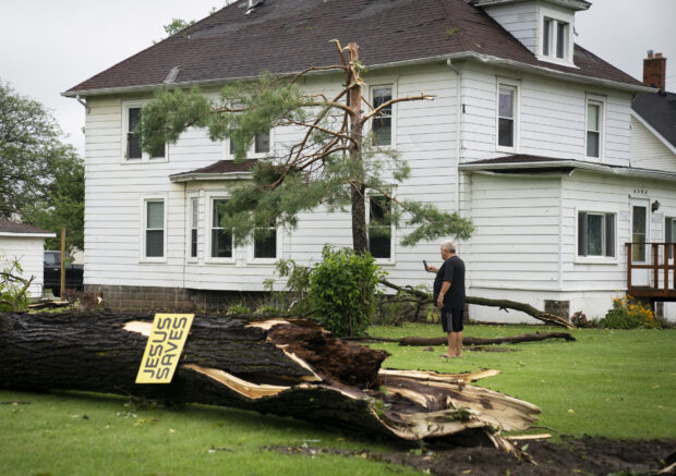 Tony Bielksi, of South Rockwood takes some photos of a neighbors fallen tree on South Huron River Drive on Friday, Aug. 25, 2023, after a heavy band of storms hit the region on Thursday. (Mandi Wright/Detroit Free Press via AP)