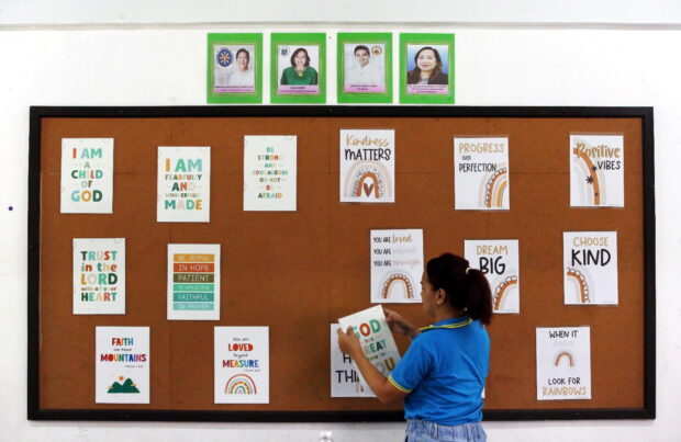 Grade 2 teacher Jennifer Rivares starts removing laminated posters with inspirational lines that she made for her students in August 2022 at the Pasig Central Elementary School during Brigada Eskwela 2023.