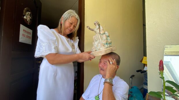 Sister Precy Aseneta-Macasaet places the image of God the Father of All Mankind on the head of a devotee on Sunday, Aug. 6. (Leo Udtohan/Inquirer Visayas)