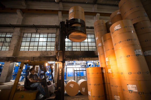 Fork lift stacking paper rolls in a printing press.