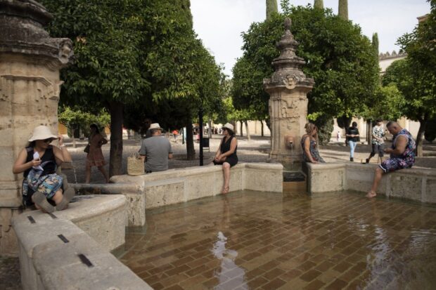 Tourists cool off in a fountain in Cordoba, southern Spain on August 8, 2023. 