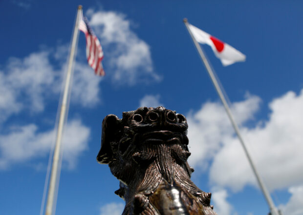 The U.S. (L) and Japanese national flags are hoisted next to a traditional Okinawan Shisa statue at the U.S. Marine’s Camp Foster in Ginowan, on the southern island of Okinawa, Japan June 18, 2016. REUTERS FILE PHOTO