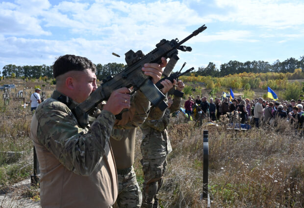 Ukrainian servicemen perform a rifle volley salute during the funeral ceremony of late Ukrainian volunteers Vadym Zabara, 51, and Sergiy Shalygin, 53, at a cemetery outskirts Kharkiv on September 22, 2023, amid the Russian invasion of Ukraine. The death toll from September 19, 2023's Russian strike on the Ukrainian city of Kupyansk has risen to eight people, authorities said, after Ukrainian rescuers found another two bodies in the rubble. (Photo by SERGEY BOBOK / AFP)