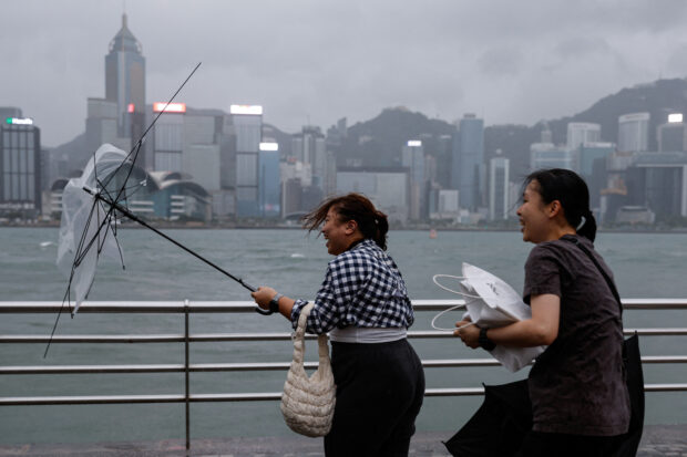 A woman holds a broken umbrella as Super Typhoon Saola approaches, in Hong Kong, China September 1, 2023. REUTERS/Tyrone Siu