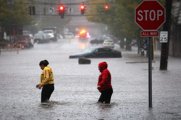 Residents walk through floodwaters during a heavy rain storm in the New York City suburb of Mamaroneck in Westchester County, New York, U.S., September 29, 2023. REUTERS/Mike Segar