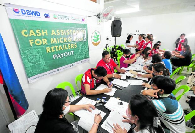 Social welfare workers distribute P15,000in cash directly to small rice retailers at the Commonwealth Market in Quezon City. 