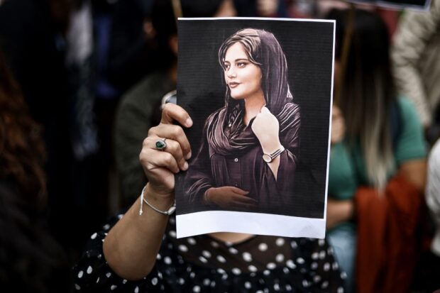 A protester holds a portrait of Mahsa Amini during a demonstration