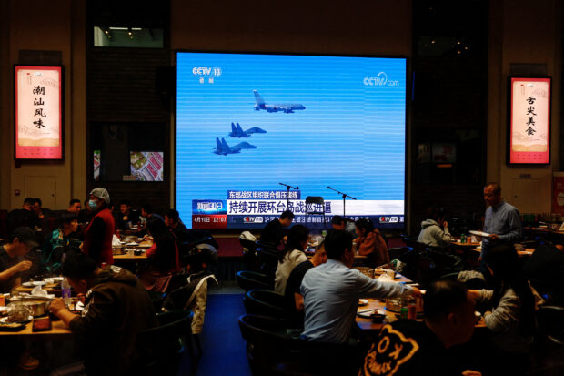 FILE PHOTO: Screen broadcasting news footage of the Eastern Theatre Command of PLA taking part in exercises around Taiwan, at a restaurant in Beijing