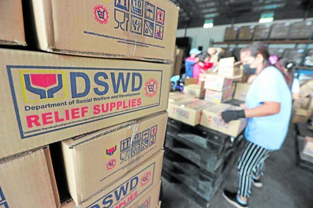 Photo of a worker stockpiling DSWD relief supplies at a DSWD warehouse.