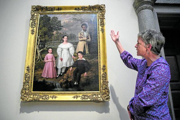 ALMOST LOST Curator Sylvia Yount stands before Jacques Amans’ “Belizaire and the Frey Children.” The painting represents one of the rarest and most fully documented American portraits of a Black individual depicted with the family of his White enslaver. —AFP