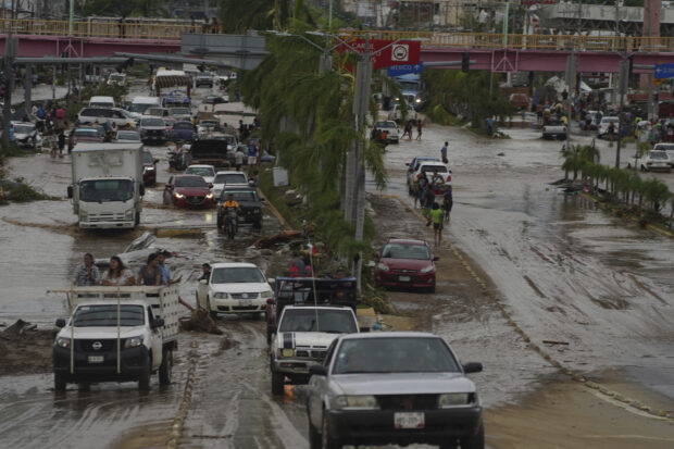 Cars cross a flood-damaged avenue after Hurricane Otis ripped through Acapulco, Mexico, Wednesday, Oct. 25, 2023. 