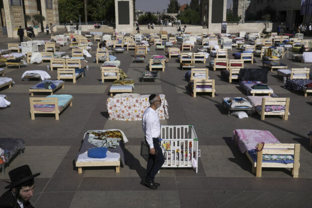 People look at more than 220 beds and items on display symbolizing those captured in a cross-border attack by Hamas militants earlier this month, in Jerusalem, Monday, Oct. 30, 2023.