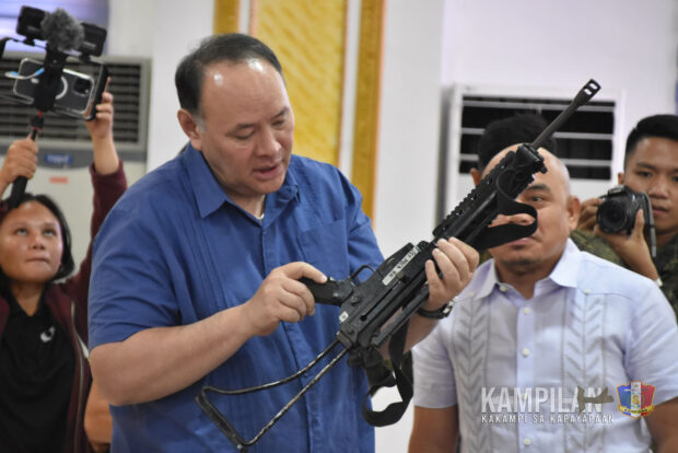 Defense Sec. Gilberto Teodoro inspects a rifle turned over by former Moro violent extremists during a visit in Buluan, Maguindnao del Sur. Teodoro witnessed the turnover of livelihood assistance from the provincial government for 50 former combatants at the provincial capital grounds on Wednesday afternoon, Oct. 11, 2023. (6th ID photo)