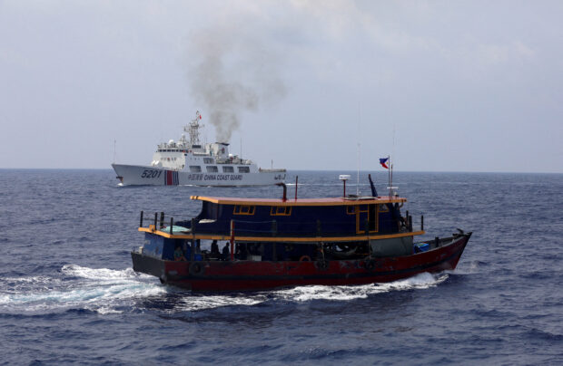 A Philippine supply boat sails near a Chinese Coast Guard ship during a resupply mission for Filipino troops stationed at a grounded warship in the South China Sea, October 4, 2023. REUTERS/Adrian Portugal/File Photo
