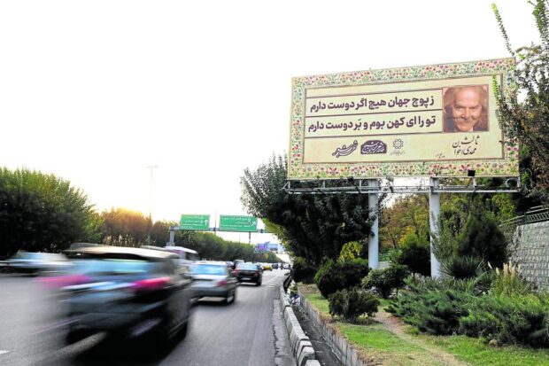ATTRACTION OR DISTRACTION?   Traffic flows under a billboard displaying excerpts from the work of Iranian poet Mehdi Akhavan-Sales along a highway in Tehran. Hundreds of these billboards featuring evocative poems are displayed all over the city and police are blaming them for an increase in road accidents. —AFP