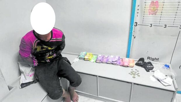 CAUGHT IN THE ACT Police on Sunday release this photo of a 22-year-old robbery suspect (with his face blotted out) seated beside the money he allegedly stole from the finance office at the warehouse of a courier service in Gerona, Tarlac, at dawn on Friday. —PHOTO COURTESY OF THE GERONA MUNICIPAL POLICE OFFICE