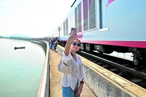 ‘IT’S NICE TO TRAVEL’ A passenger of Thailand’s popular “floating train” takes a selfie along the railway tracks during a stop in the middle of Pasak Jolasid Dam. —AFP