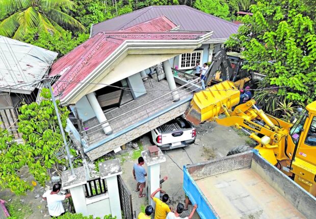 AFTERMATH A bulldozer lifts a portion of the collapsed balcony of a house in Malapatan town, Sarangani province, while a truck pulls a vehicle pinned underneath that debris. —ERWIN M. MASCARIÑAS
