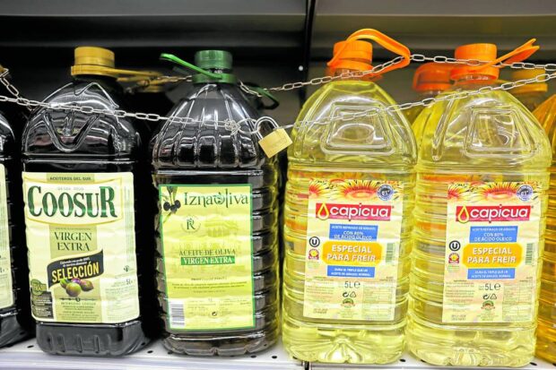 PRECIOUS Olive and sunflower oil bottles are displayed for sale, protected by a padlock and a chain to prevent theft in a Tu Super Suma supermarket in Malaga, Spain, on Oct. 23. —REUTERS