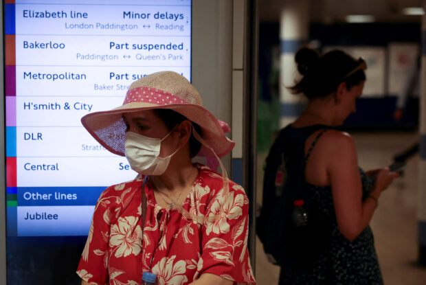 File photo: A woman wearing a face mask stands next to a tube train notice board in London, Britain, July 18, 2022. 