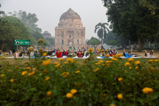 People perform yoga at Lodhi Garden on a smoggy morning in New Delhi