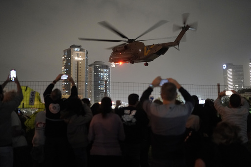 A group of Israelis watch as a helicopter carrying hostages released from the Gaza Strip lands at the helipad of the Schneider Children's Medical Center in Petah Tikva, Israel, Sunday Nov. 26, 2023. The cease-fire between Israel and Hamas was back on track Sunday as the militants freed 17 more hostages, including 14 Israelis and the first American, in exchange for 39 Palestinian prisoners in a third set of releases under a four-day truce. (AP Photo/Leo Correa)