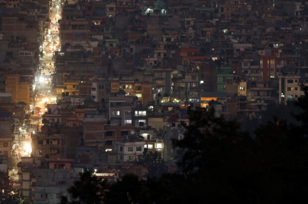 Light illuminates a street between the cluster of residential buildings in Kathmandu
